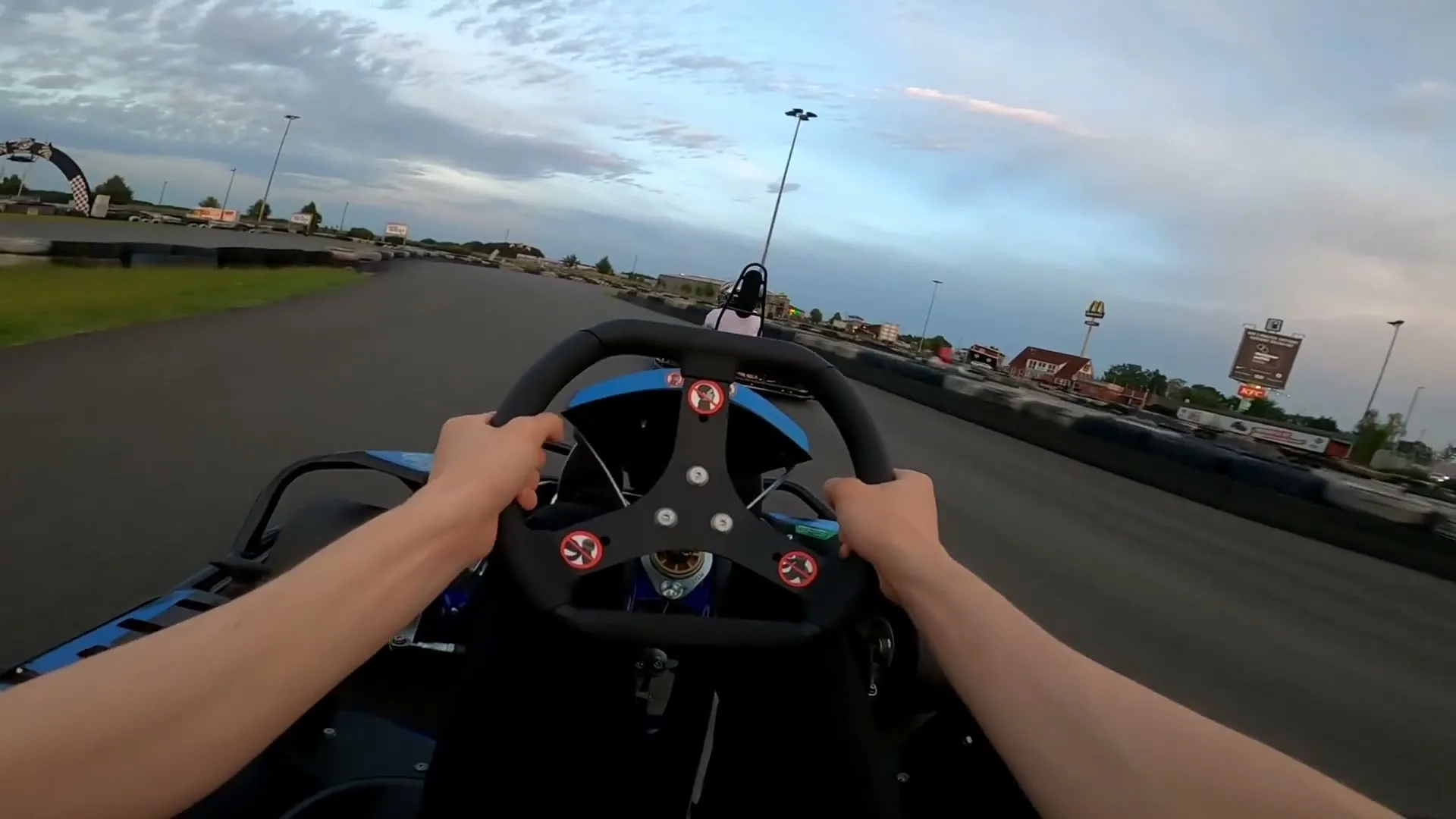 Blick über das Lenkrad eines Karts auf die Strecke, vorn ein weiteres Kart
